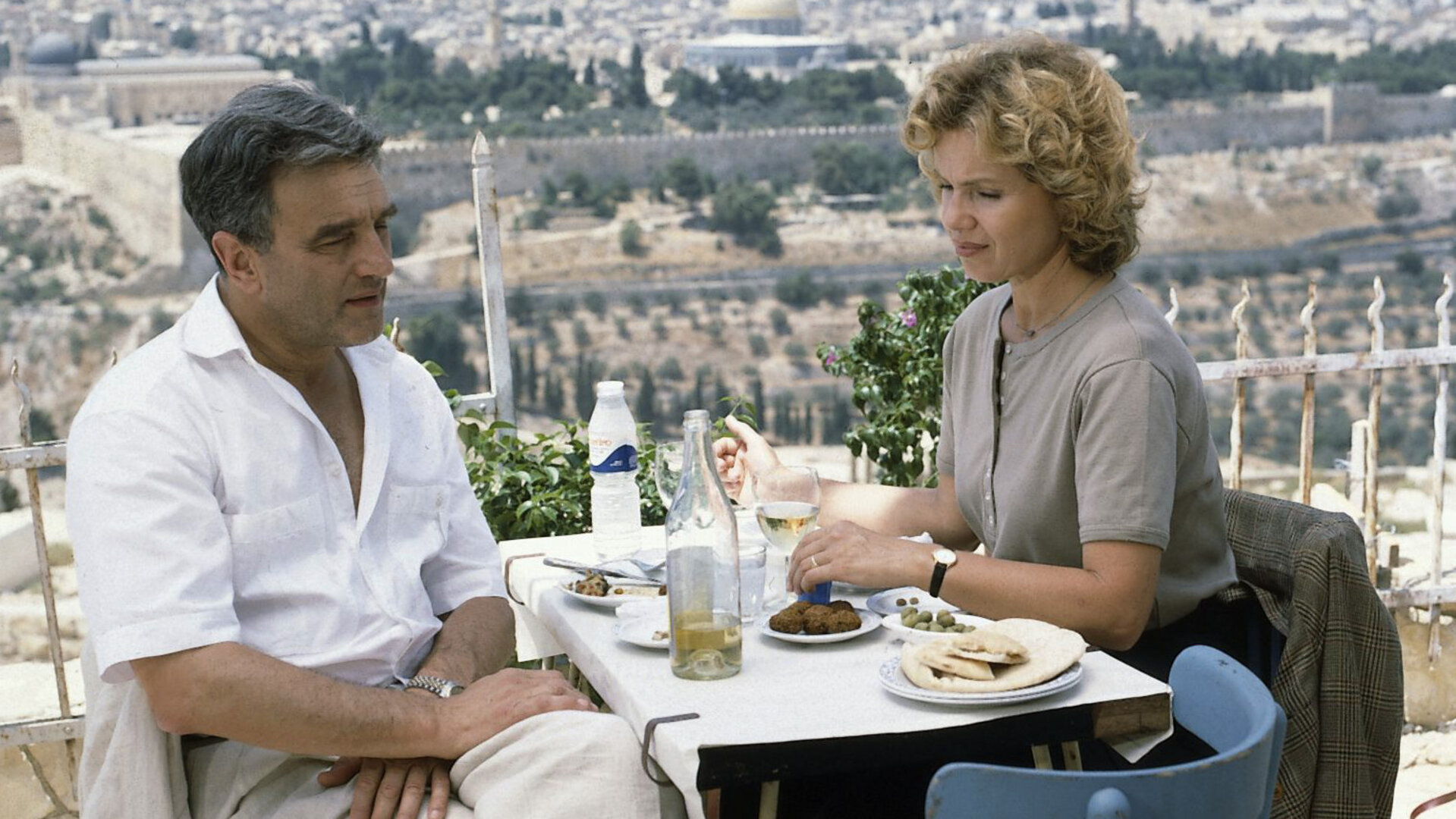 "Diese Drombuschs - Die Heimkehr“: Martin (Michael Degen) und Vera (Witta Pohl) sitzen auf einer Terrasse über den Dächer von Jerusalem an einem Tisch und essen gemeinsam.