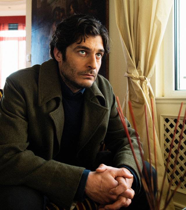 "Survivors - Freundschaften": Luca (Lino Guanciale) sitzt in seinem Wohnzimmer auf der Couch und blickt sorgenvoll nach vorne.