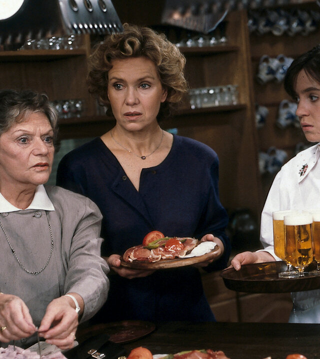 "Diese Drombuschs - Späte Einsicht": Oma (Grete Wurm), Vera (Witta Pohl) und Yvonnche (Anja Jaenicke) stehen nebeneinander hinter dem Tresen und unterhalten sich.