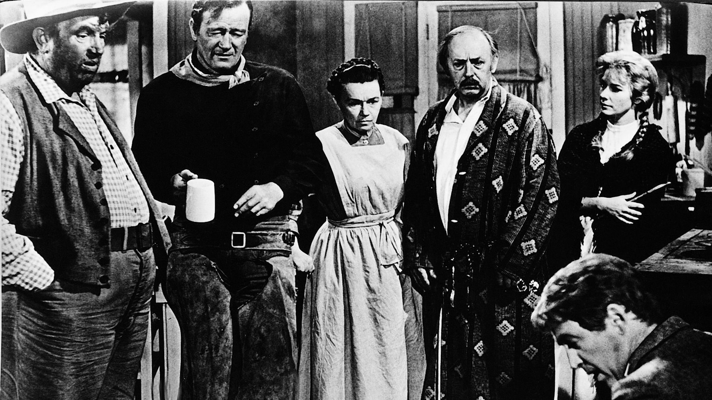 "Der Mann, der Liberty Valance erschoss": Der junge Rechtsanwalt Ransom Stoddard (James Stewart, r.) ist in der Nähe des Pionierstädtchens Shinbone im wilden Westen von dem Banditen Liberty Valance brutal überfallen und zusammengeschlagen worden. Der Tierzüchter Tom Doniphon (John Wayne, 2.v.l.), ebenfalls ein gefürchteter Revolverheld, hat ihn gefunden und nach Shinbone gebracht. Sheriff Appleyard (Andy Devine, l.) hat wenig Lust, etwas gegen Liberty Valance zu unternehmen. Das Ehepaar Ericson (Jeanette Nolan, M. und John Qualen, 2.v.r.) und dessen Tochter Hallie (Vera Miles, r.) aber pflegen Ransom Stoddard gesund.