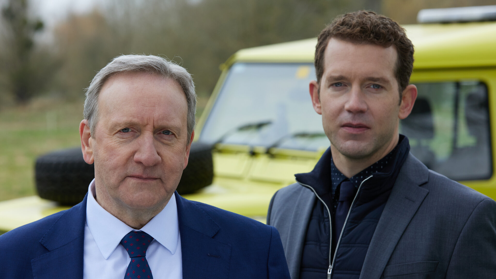 "Inspector Barnaby - Schätze der Finsternis": Nahaufnahme: DCI John Barnaby (Neil Dudgeon) und DS Jamie Winter (Nick Hendrix) stehen im Freien vor einem Auto und schauen nach vorne.