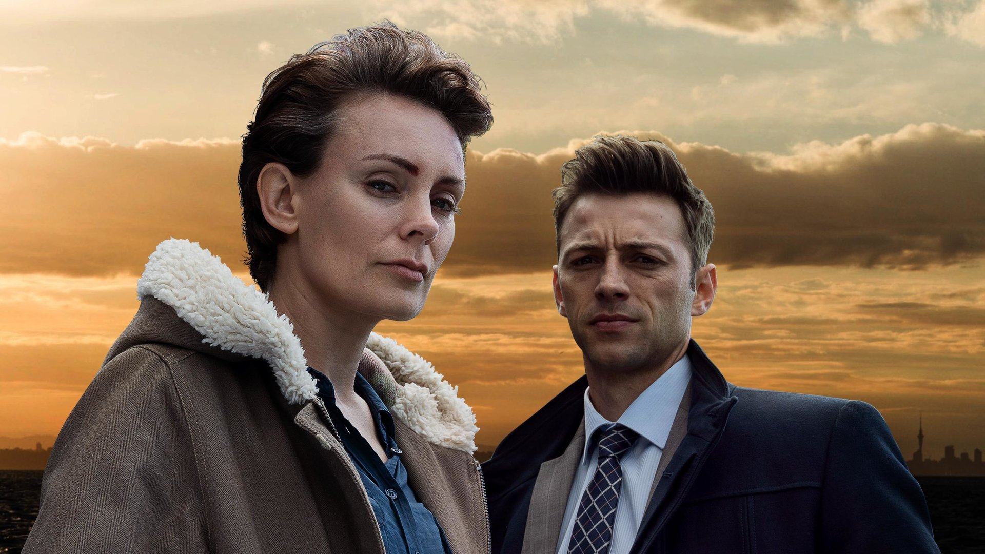Auckland Detectives  - Tödliche Bucht: Aus dem Nichts": Detective Senior Sergeant Jessica Savage (Kate Elliott) und ihr Kollege Detective Sergeant Justin Harding (Ido Drent) in Nahaufnahme vor einem Sonnenuntergang.