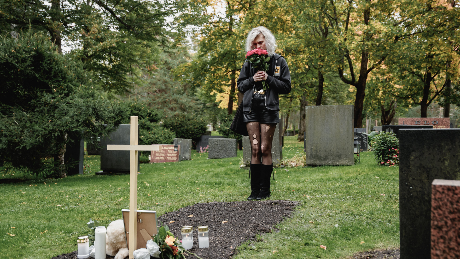 "Cryptid - Der Selbstversuch von Ester": Ester (Maja Johanna Englander) steht vor einem Grab. Darauf stehen Kerzen und ein Foto.