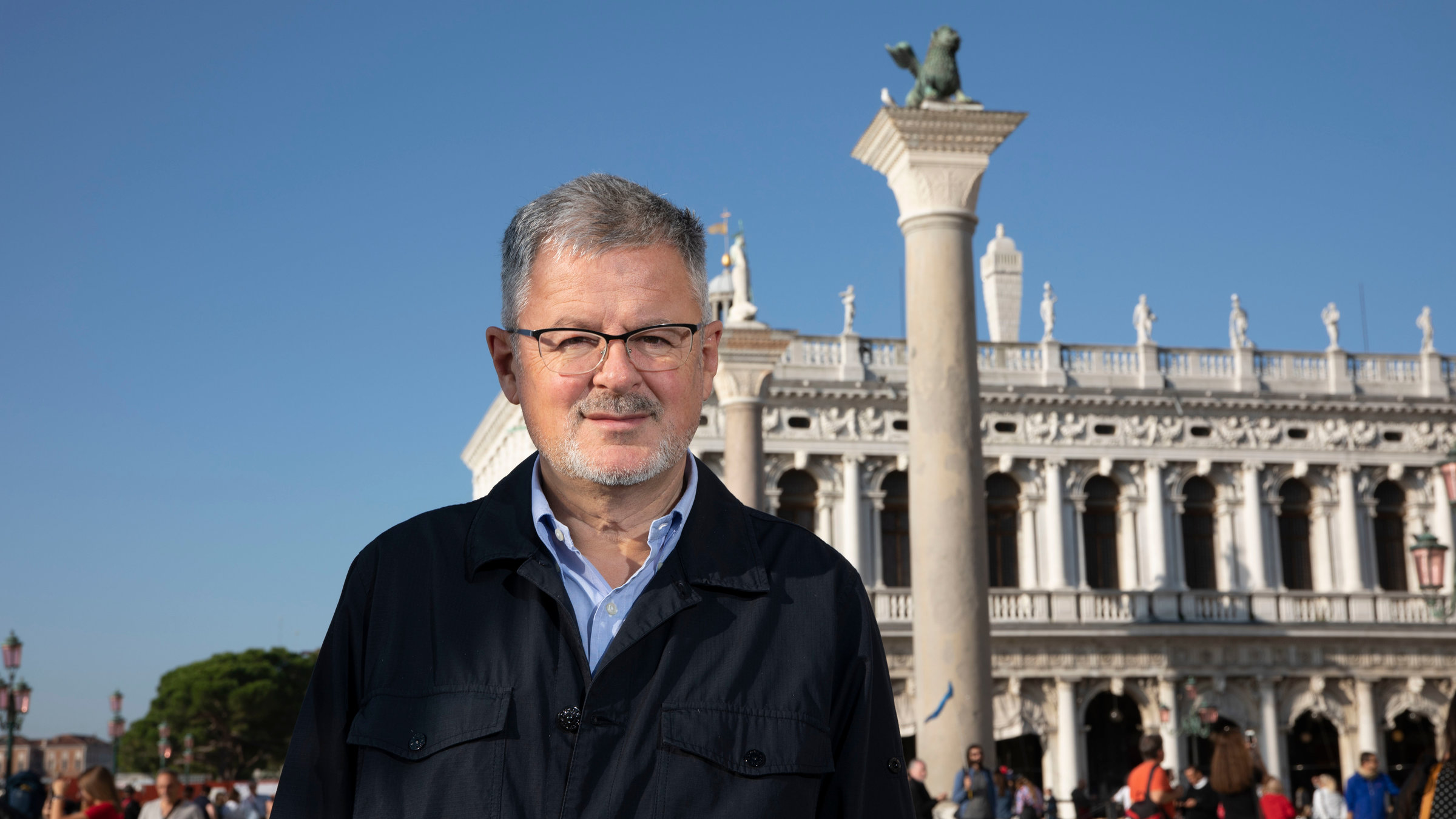 "Terra X: Welten-Saga - Die Schätze Europas": Christopher Clark steht auf dem Markusplatz in Venedig vor einer Säule, auf der ein Markuslöwe thront.