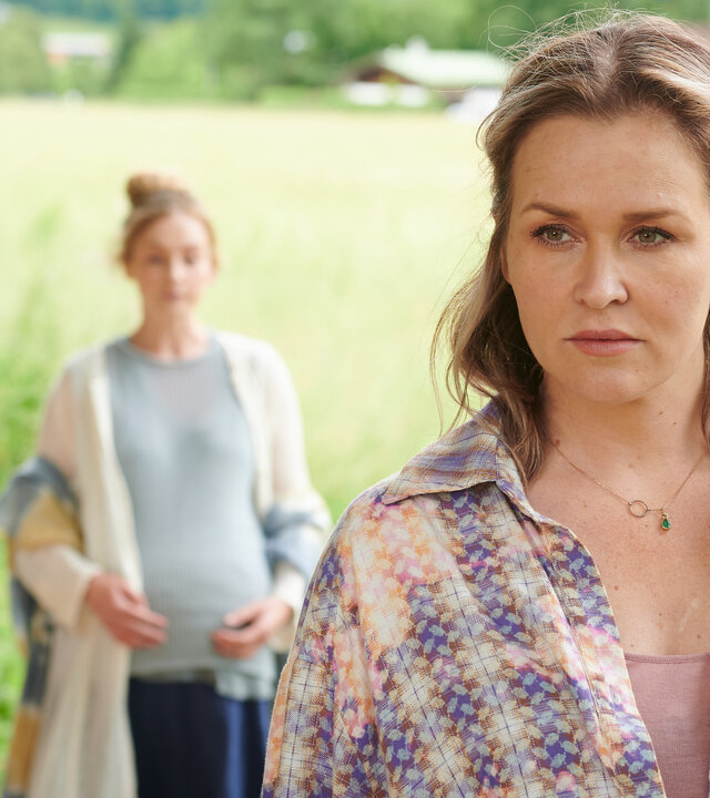 "Lena Lorenz - Freiheit": Auf einer Wiese steht Lena Lorenz (Judith Hoersch) im Vordergrund. Ihr Blick drückt Besorgnis aus. Im Hintergrund stehen Lilly Waldhauser (Teresa Klamert) und Marthe Gerber (Doris Schretzmayer).