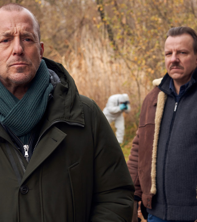 "Ingo Thiel - Ein Mädchen wird vermisst": Die beiden Ermittler Ingo Thiel (Heino Ferch) und Winni (Ronald Kukulies) stehen voreinander im Wald. Hinter ihnen ein Kollege von der Spurensicherung.