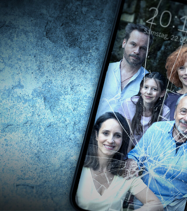 "Stubbe - Familie in Gefahr": Auf einem blau-grauen Untergrund liegt ein Smartphone. Auf dem Display sind Helge (Wanja Mues), Christiane (Stephanie Stumph), Caro (Greta Kasalo), Stubbe (Wolfgang Stumph) und Marlene (Heike Trinker) abgebildet. Das Glas des Display zeigt einige Sprünge auf.
