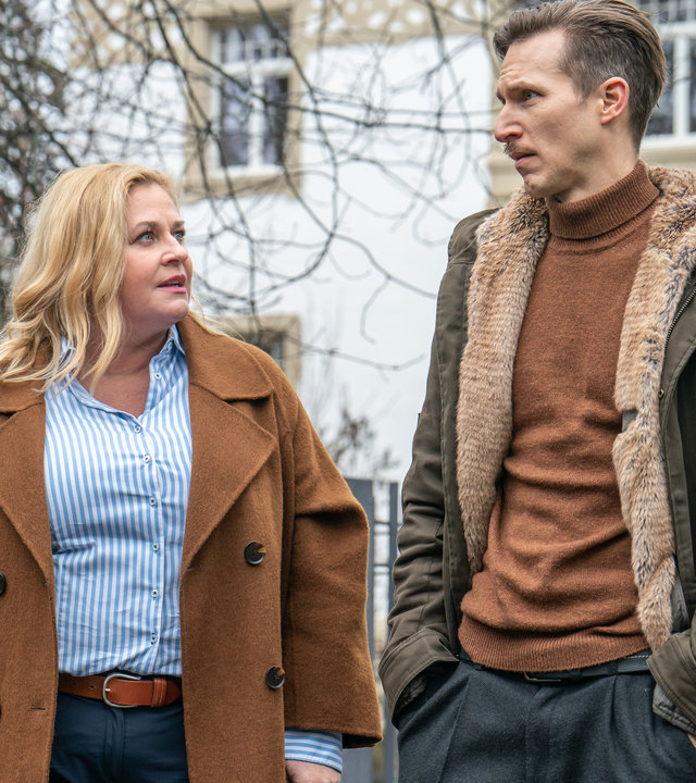 "SOKO Leipzig - Tödliches Schweigen": Dagmar Schnee (Petra Kleinert) und Moritz Brenner (Johannes Hendrik Langer) laufen eine Einfahrt entlang. Hinter ihnen sieht man einen Metallzaun und Häuser.