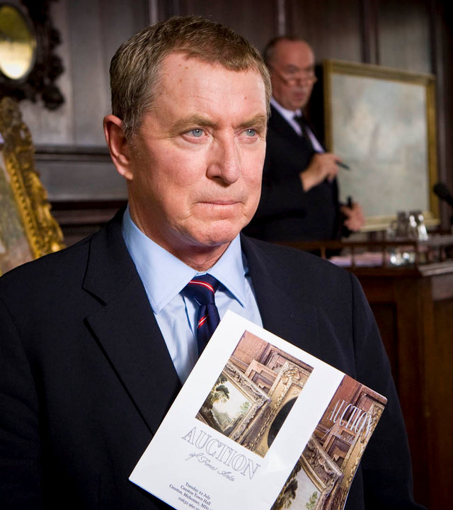 "Inspector Barnaby - Morden ist auch eine Kunst": Nahaufnahme von DCI Tom Barnaby (John Nettles) mit einem Auktionskatalog in der Hand. Hinter ihm steht ein Auktionator an seinem Pult.