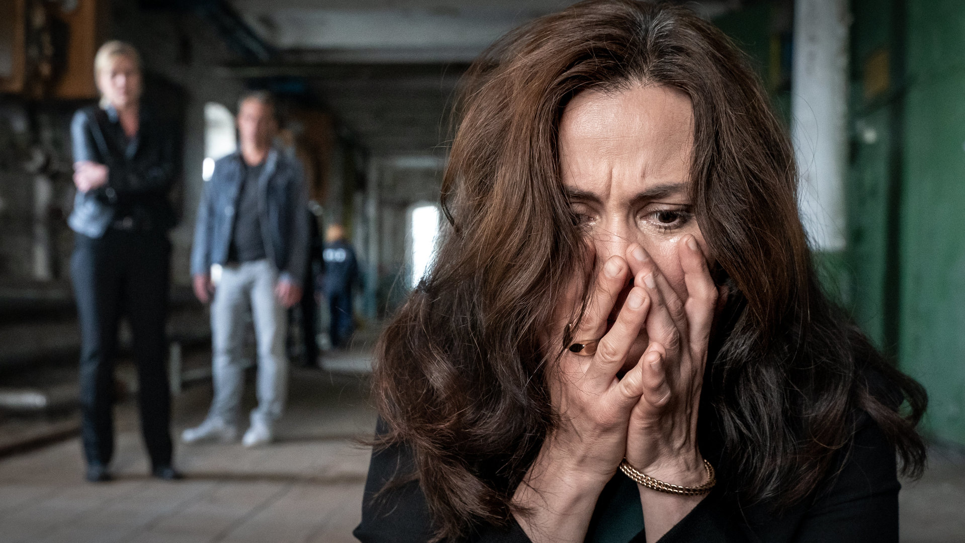 "SOKO Leipzig: Sag mir wo du stehst": Dr. Dilan Soray (Idil Üner) befindet sich zusammen mit Ina Zimmermann (Melanie Marschke) und Jan Maybach (Marco Girnth) in einer alten Fabrikhalle. Dilan Soray ist vordergründig im Bild hält entsetzt beide Hände vor ihr Gesicht. Jan und Ina halten sich eher im Hintergrund auf.