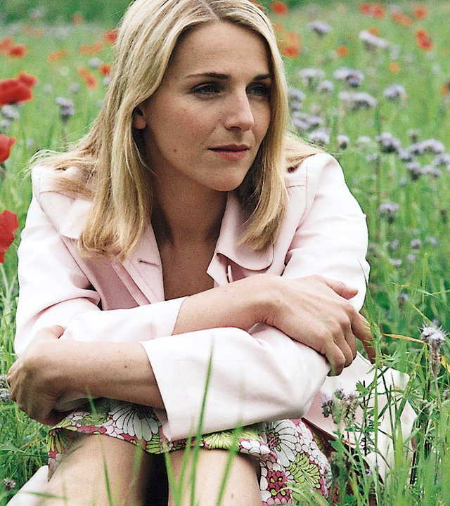 "Bianca - Wege zum Glück: Kapitel 195": Auf einer Sommerwiese: Bianca (Tanja Wedhorn) sitzt im Gras mit vielen bunten Sommerblumen um sie herum und hängt ihren Gedanken nach.