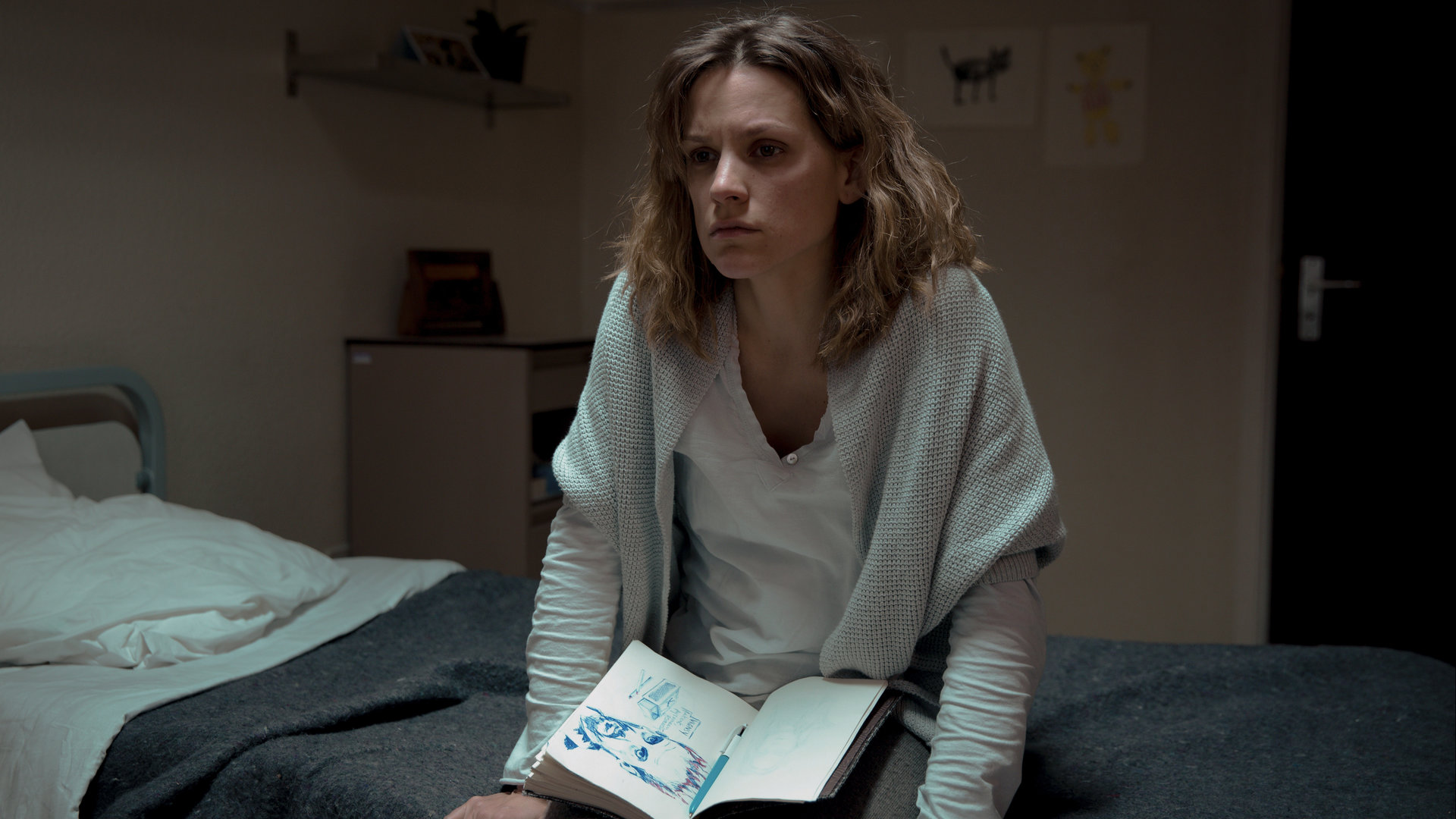 "Tabula Rasa - Die Wände haben Ohren": Annemie D'Haeze (Veerle Baetens), genannt Mie, sitzt mit ihrem Notizbuch auf ihrem Bett in der Anstalt für psychisch Kranke.