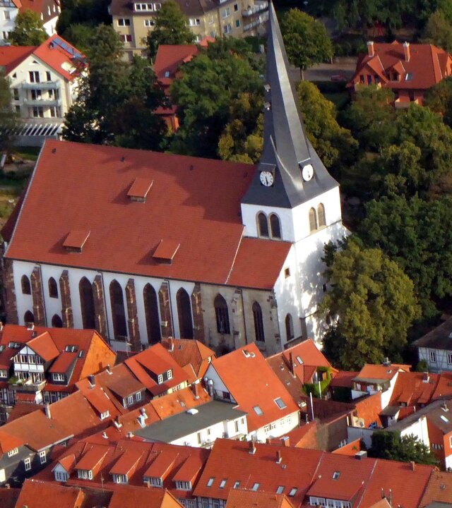 Evangelischer Gottesdienst - "Lehn dich einfach an": Blick von schräg oben auf die Kirche St. Sixti in Northeim: Die weiße Kirche mit rotem Dach und einem spitz zulaufenden Kirchturm liegt inmitten der Altstadt und ist umgeben von Fachwerkhäusern und von Bäumen.