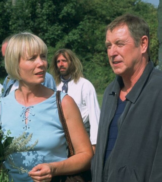 "Inspector Barnaby - Grab des Grauens": Joyce Barnaby (Jane Wymark) und DCI Tom Barnaby (John Nettles) stehen in einem Garten zusammen und unterhalten sich. Joyce hat einen Blumenstrauß in der Hand. Im Hintergrund sind weitere Personen zu erkennen.