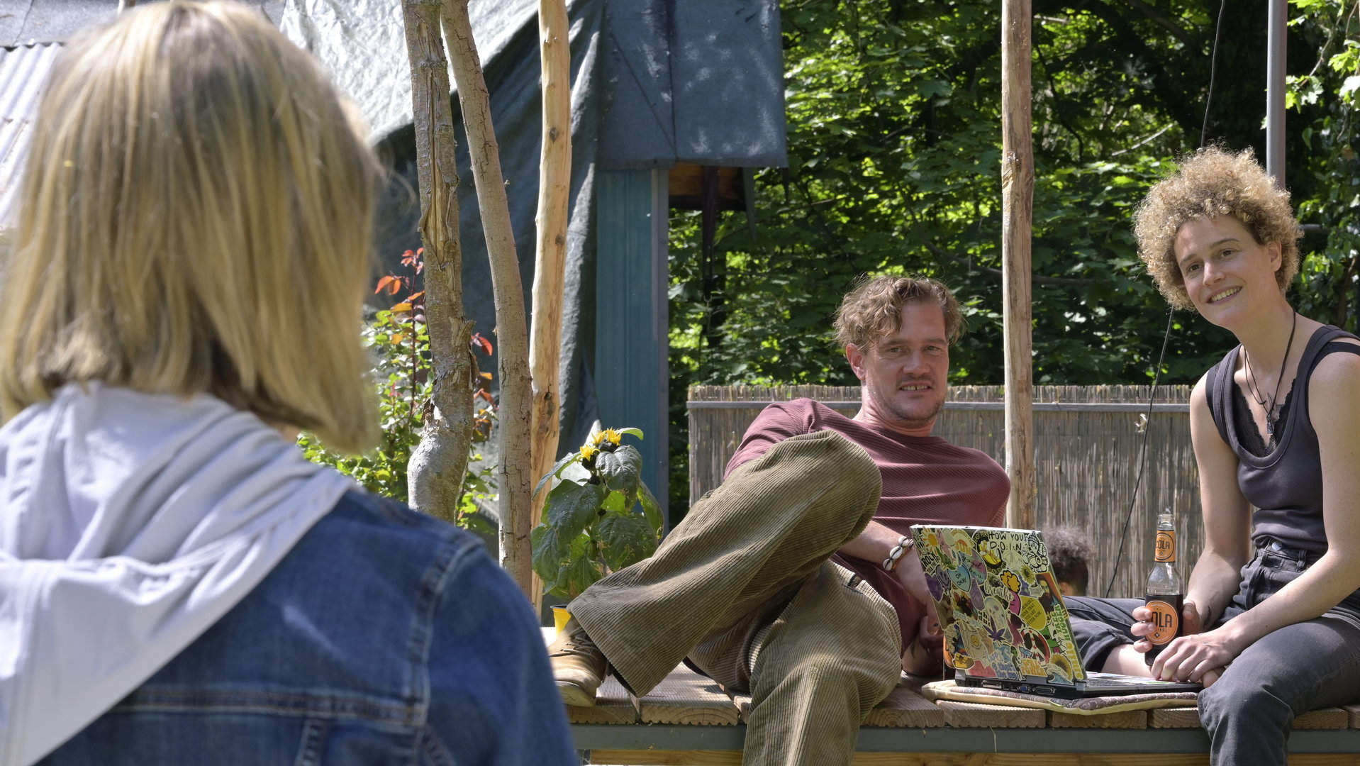 "SOKO Potsdam - Alte Freunde": Tamara (Anja Pahl) stellt Jo (Karen Dahmen) und Harry (David Bredin) draußen zur Rede. Jo und Harry sitzen auf einem Tisch mit einem Laptop vor sich. Tamara blickt zu ihnen und steht mit dem Rücken zur Kamera.