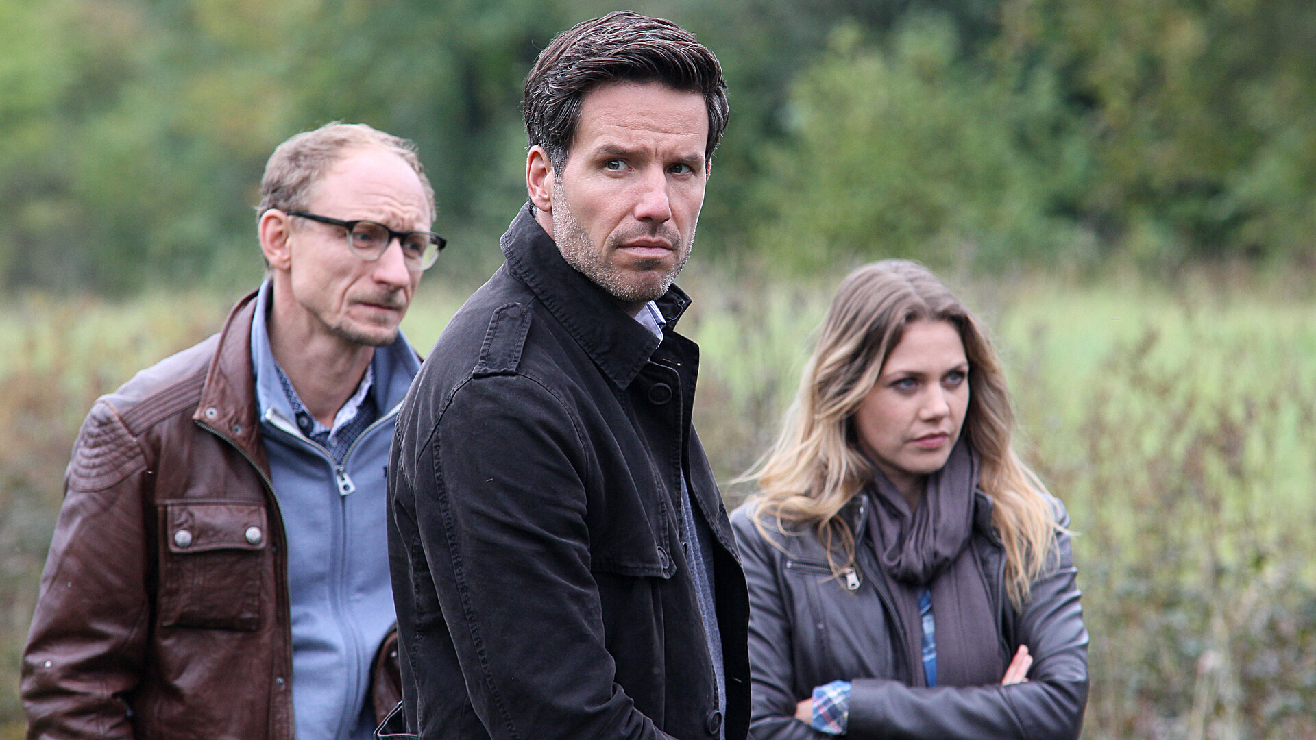 "Mordsfreunde": Kai Ostermann (Michael Schenk) und das Ermittler-Duo Oliver von Bodenstein (Tim Bergmann) und Pia Kirchhoff (Felicitas Woll) stehen auf einer Wiese.