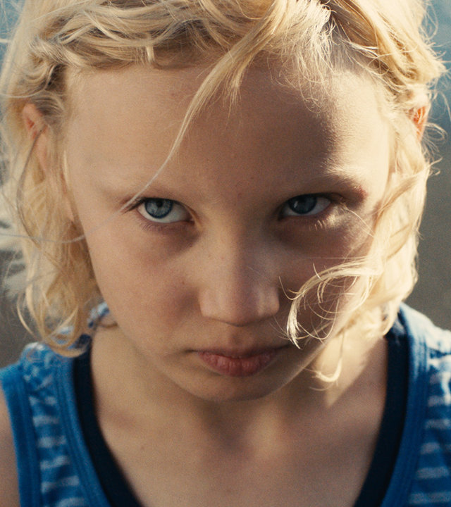"Die Tochter":  Luca (Helena Zengel) in einem ärmellosen T-Shirt steht am Strand und schaut mit ernstem Blick nach oben.