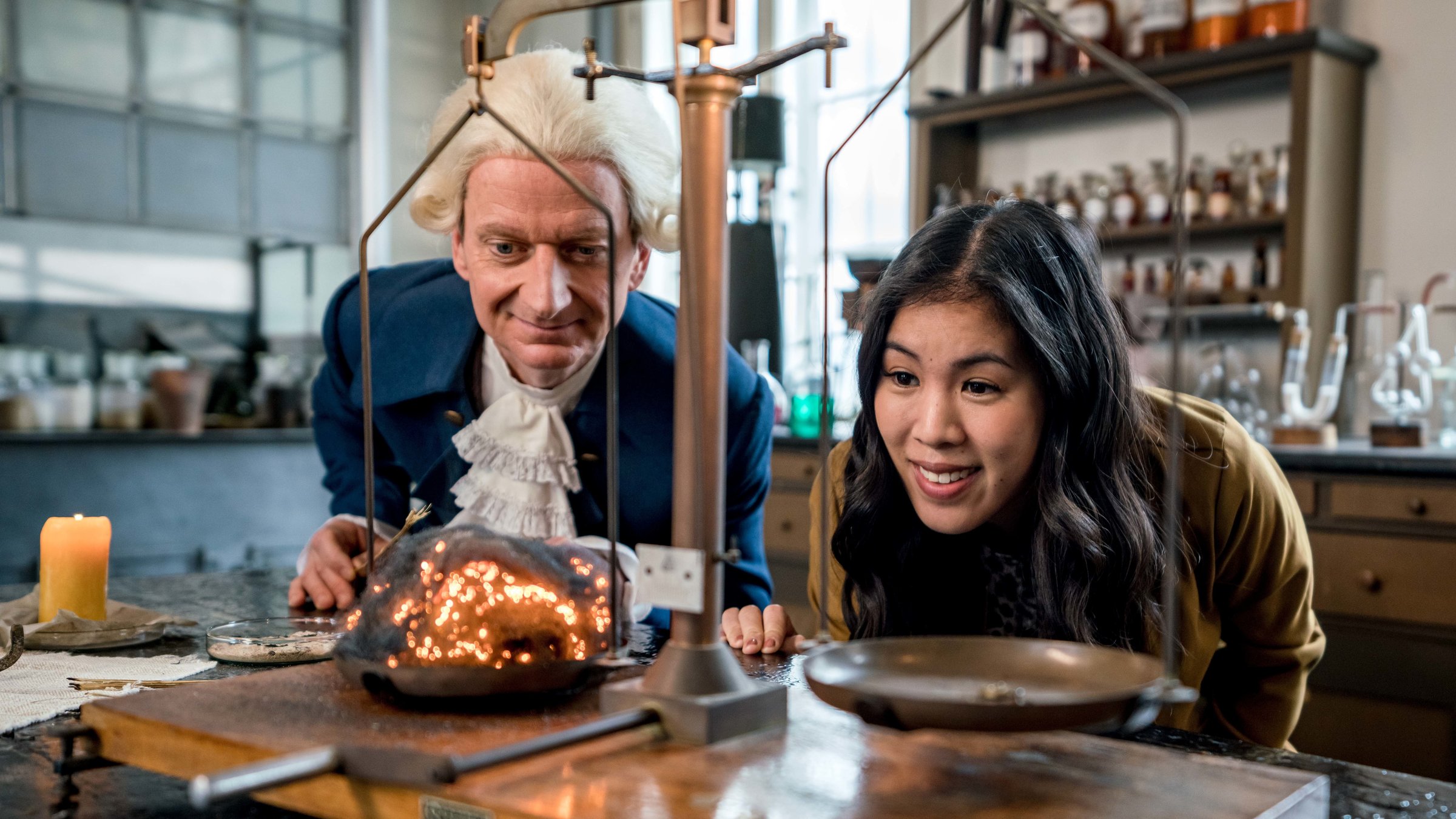 "Terra X: - Wunderwelt Chemie - Die Bausteine der Natur": Mai Thi Nguyen-Kim und Michael Kessler (als Darsteller des Wissenschaftlers Joseph Priestley) blicken in einem Labor auf eine Waage.