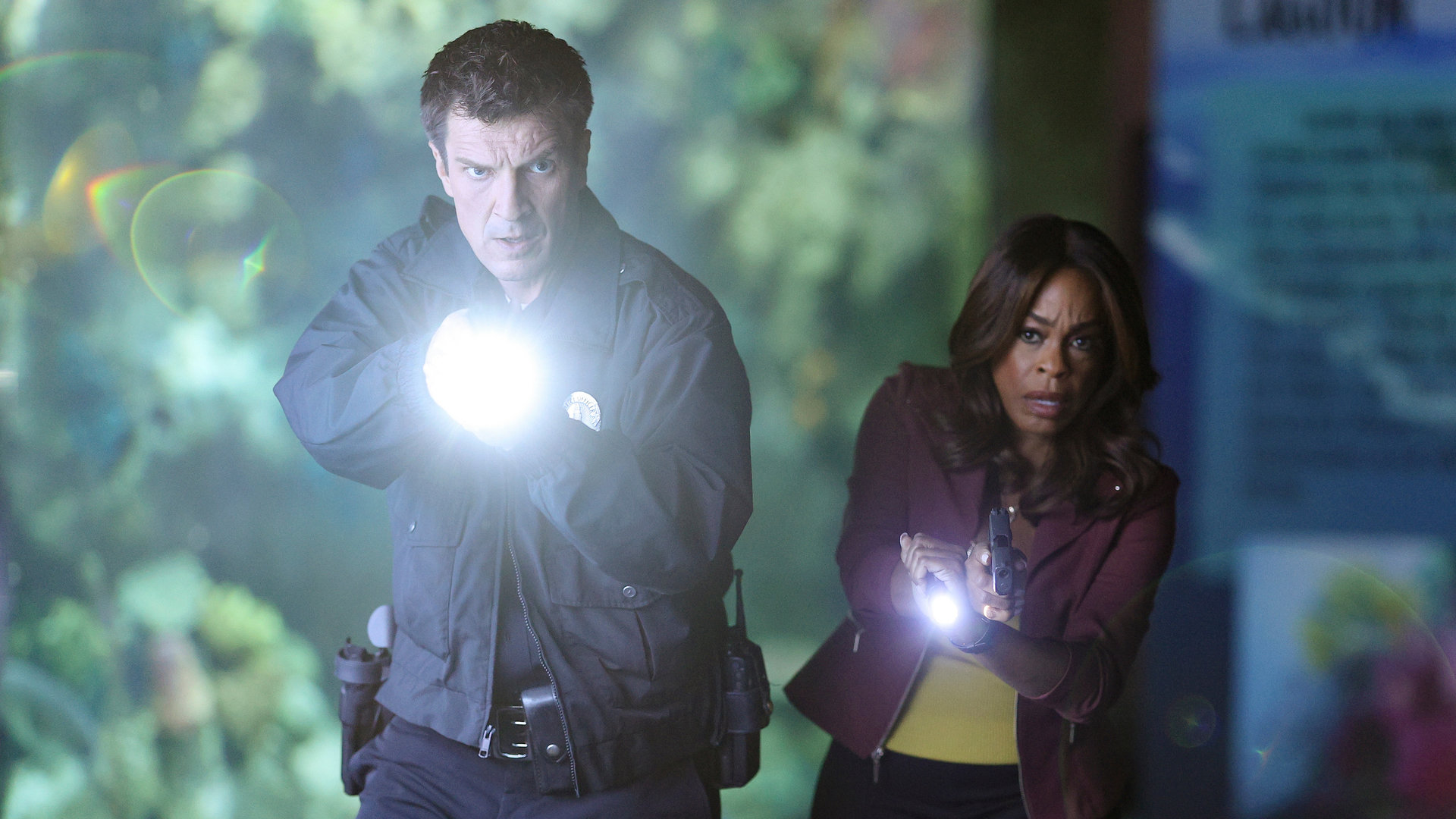"The Rookie - FBI": Nolan (Nathan Fillion) und Clark (Niecy Nash) laufen mit gezogener Waffe durch ein dunkles Aquarium.