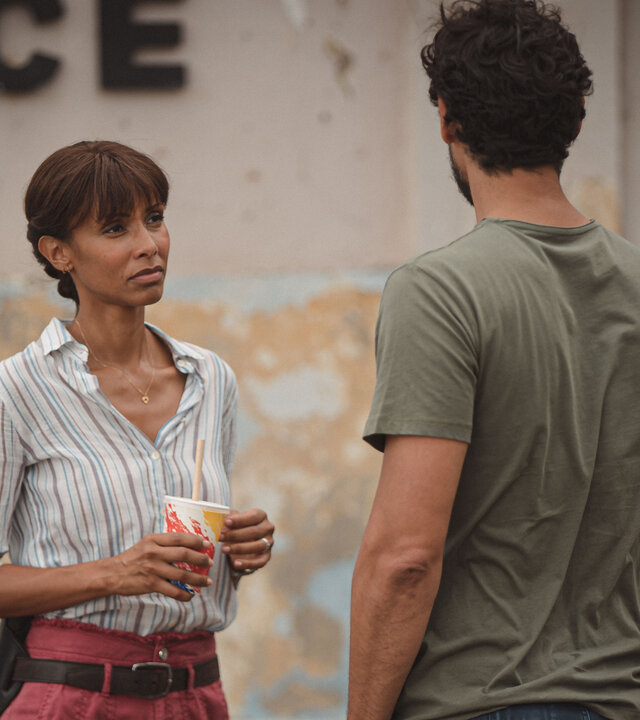 "Deadly Tropics - Die Stimme der Nacht": Mélissa (Sonia Rolland) und Cyril (Stany Coppet) stehen sich vor dem Polizeigebäude gegenüber. Mit einem Getränkebecher in der Hand schaut Mélissa Cyril betrübt an.
