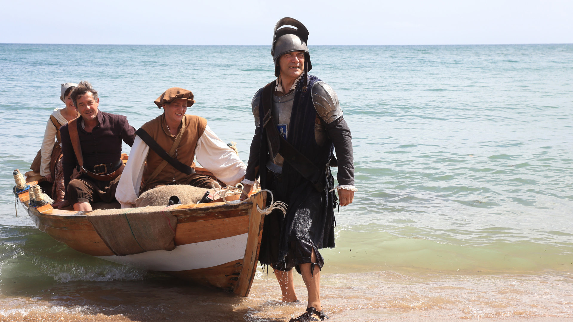 "Death in Paradise -  Ein bitterer Nachgeschmack": Teresa (Amanda Root), Henri (Georges Corraface), Ryan (Tyger Drew-Honey) und Francis Davis (Adrian Lukis) tragen altertümliche Kostüme und landen mit einem Boot am Ufer an.