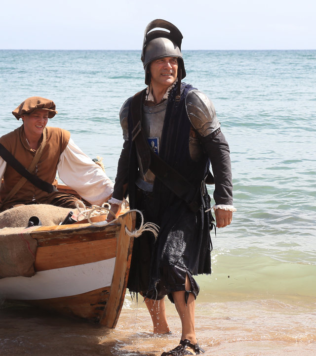 "Death in Paradise -  Ein bitterer Nachgeschmack": Teresa (Amanda Root), Henri (Georges Corraface), Ryan (Tyger Drew-Honey) und Francis Davis (Adrian Lukis) tragen altertümliche Kostüme und landen mit einem Boot am Ufer an.