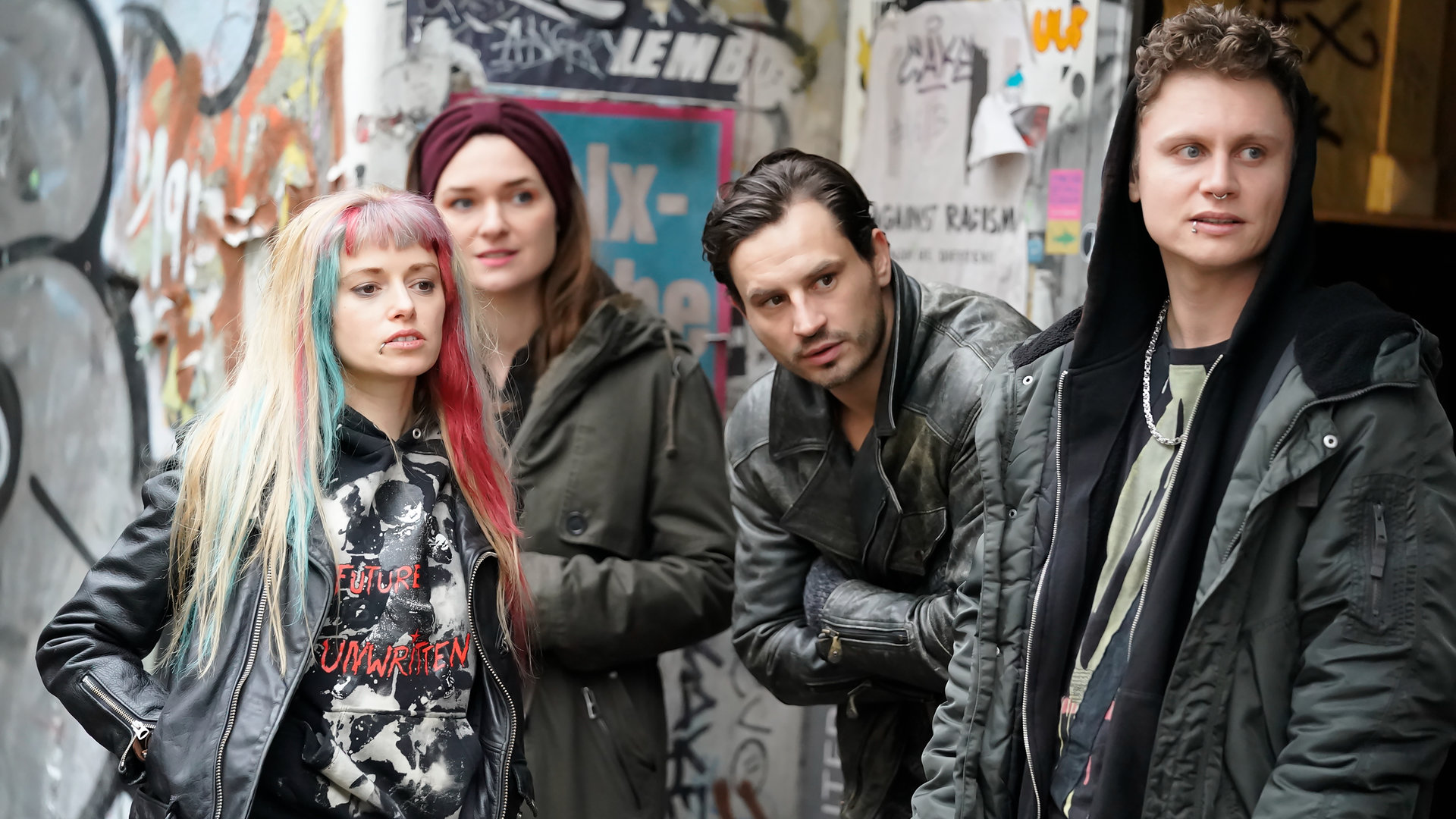 "Letzte Spur Berlin - Klassenkampf": Doro Herrmann (Anne-Marie Waldeck), Lucy Elbe (Josephin Busch), Giovanni Lazzari (Jaime Ferkic) und Niklas Stöckle (Rafael Gareisen) stehen nebeneinander vor einer mit Graffiti besprühten Häuserwand. Sie blicken alle in eine Richtung.