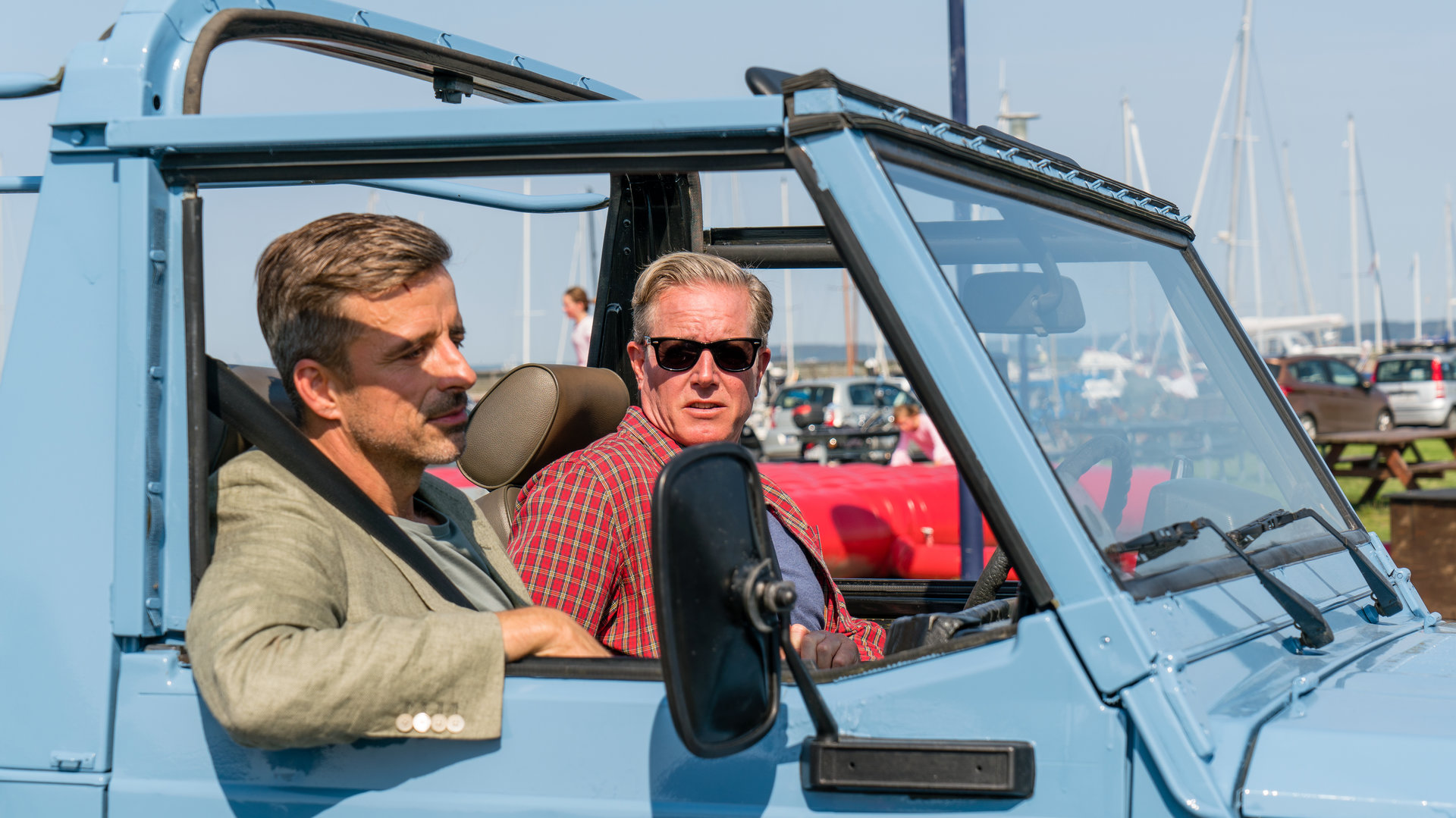 "Dan Sommerdahl - Mörderisches Foul": Flemming (André Babikian) und sein Kollege Dan (Peter Mygind) fahren gemeinsam in einem hellblauen Jeep.