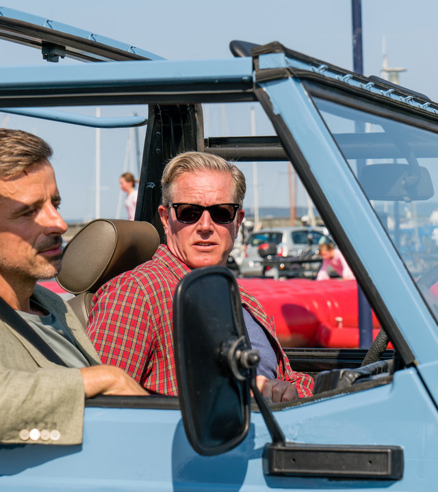 "Dan Sommerdahl - Mörderisches Foul": Flemming (André Babikian) und sein Kollege Dan (Peter Mygind) fahren gemeinsam in einem hellblauen Jeep.