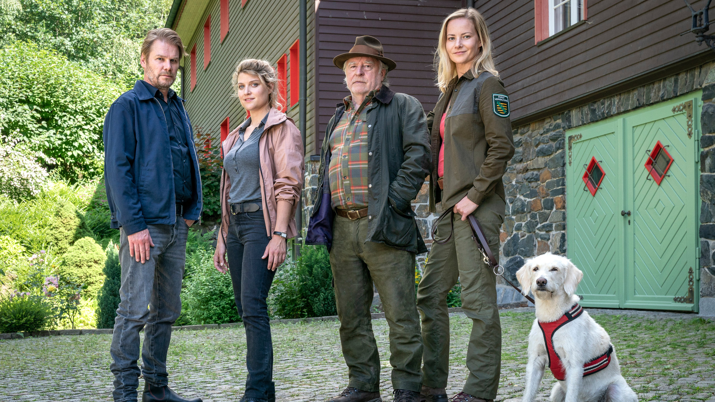 "Erzgebirgskrimi - Der Tote im Burggraben": Robert Winkler (Kai Scheve), Karina Szabo (Lara Mandoki), , Georg Bergelt (Andreas Schmidt-Schaller), Saskia Bergelt (Teresa Weißbach) und der weiße Hund Wolke stehen vor dem Forsthaus.