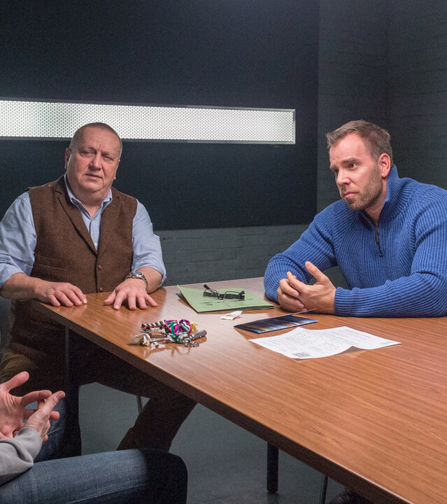 "SOKO Wismar – Täter Timmermann": Timmermann (Mathias Junge), in Zivil, wird von Jan Reuter (Udo Kroschwald), Lars Pöhlmann (Dominic Boeer) und Karoline Joost (Nike Fuhrmann) im Vernehmungsraum befragt. Vor Timmermann auf dem Tisch liegen ein Schlüsselbund und verschiedene Papiere.