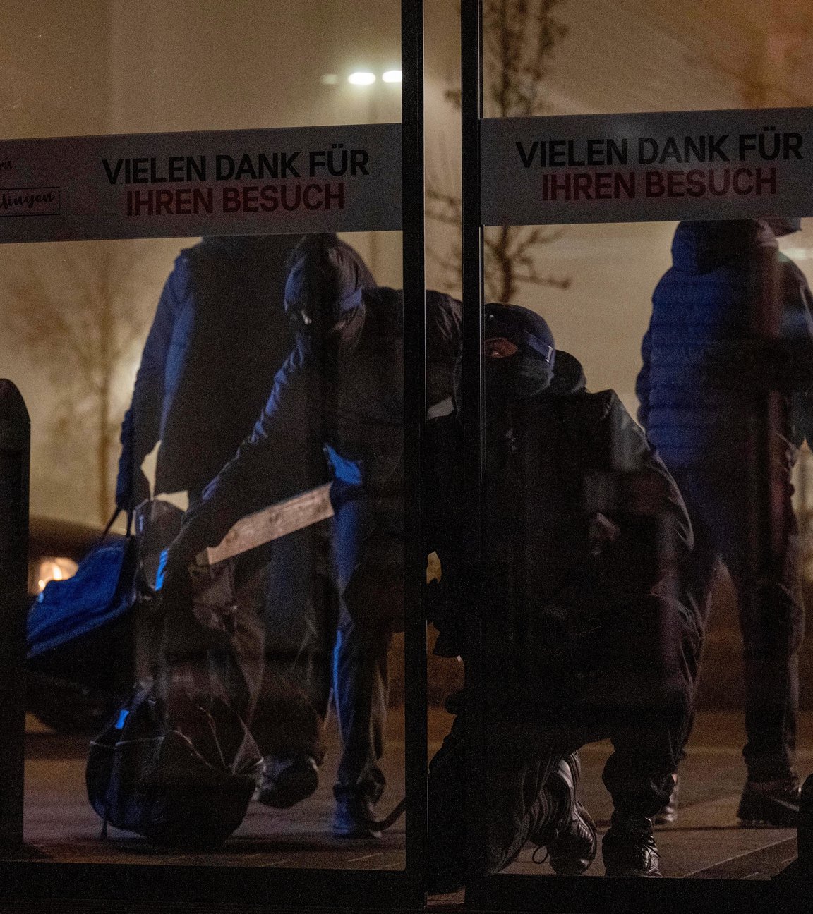 "Aktenzeichen XY... Ungelöst": Nachgespielte Szene. Nacht vor einem Einkaufszentrum versuchen vier maskierte Männer sich Eintritt zu verschaffen durch eine Glastür.