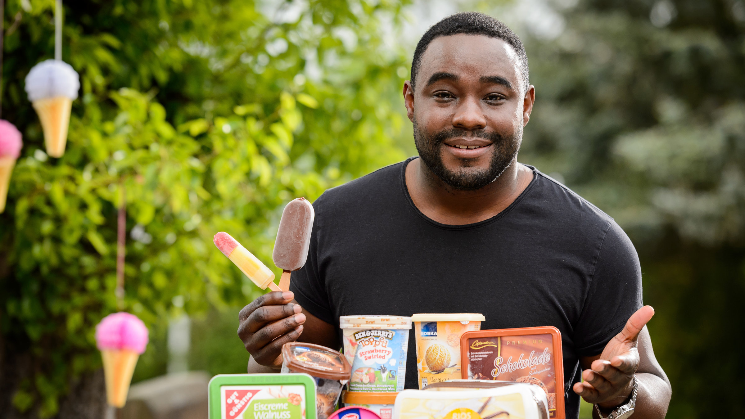 "ZDFzeit - Langnese, Schöller & Co.": Nelson Müller hinter einem Tisch, auf dem Speiseeis von unterschiedlichen Firmen steht.