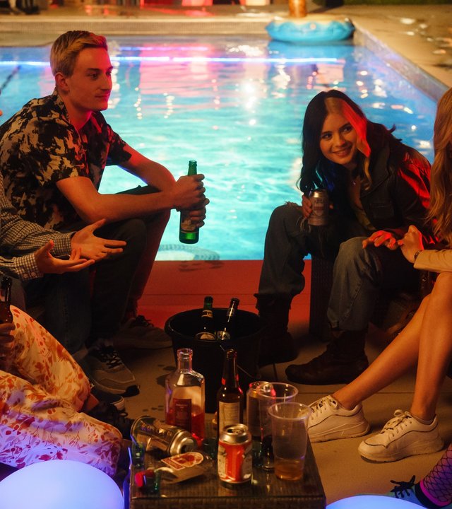 "Tell me everything: Schlaf": Neve (Lauryn Ajufo), Louis (Spike  E. Fearn), Jonny (Eden H. Davies), Regan (Tessa Lucille), Zia (Carla Woodcock) und Mei (Callina Liang) sitzen vor einem Pool auf dem Boden unterhalten sich ausgelassen und trinken Alkohol.