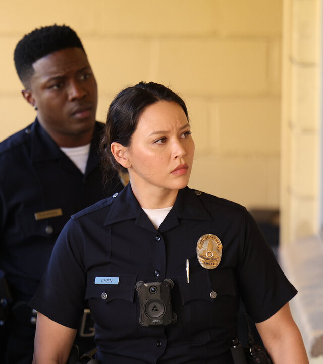 "The Rookie - Rückschlag": Officer Lucy Chen (Melissa O'Neil) und Aaron Thorsen (Tru Valentino) laufen konzentriert an der Hauswand eines Motels entlang.
