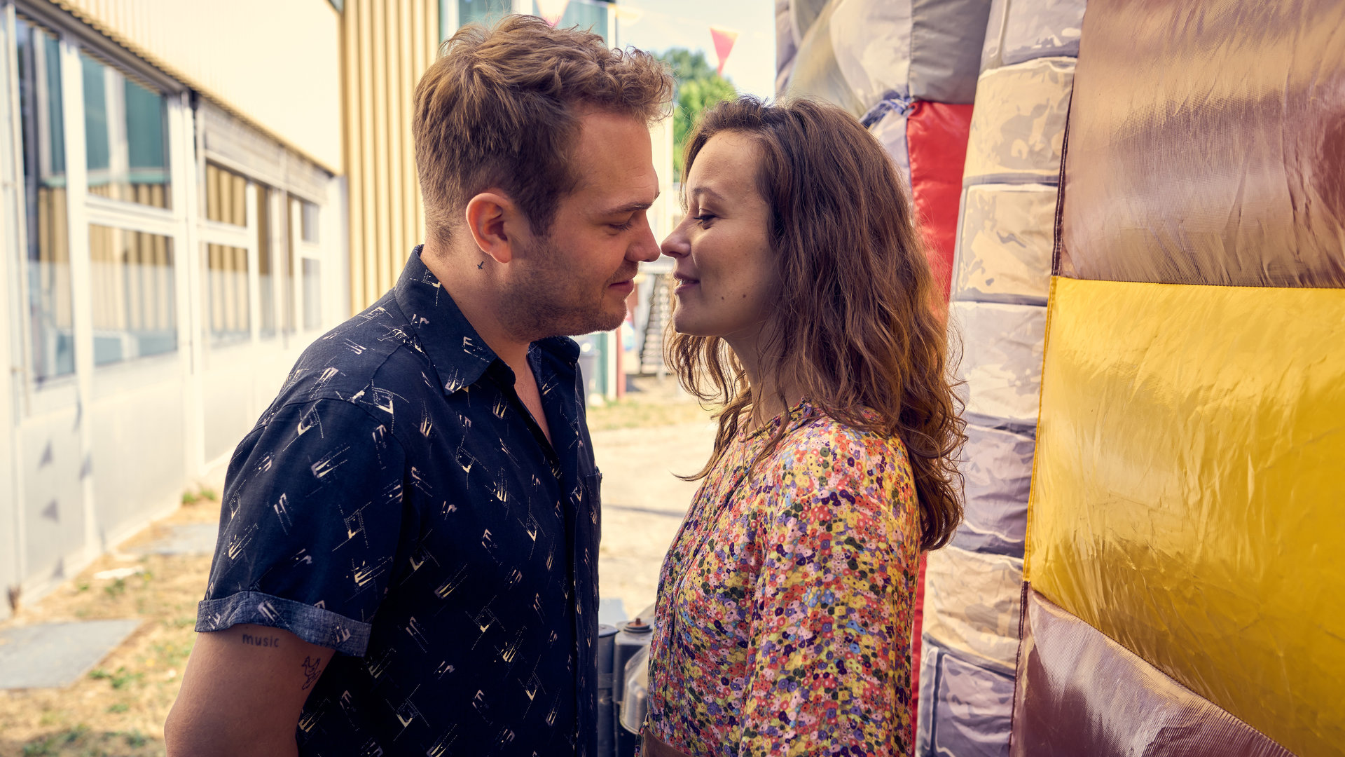 "Like a Loser - Ist das was Ernstes?": Julian (Ben Münchow) und Marie (Tinka Fürst) sind kurz davor, sich zu küssen. Sie stehen dabei hinter einer Hüpfburg auf dem Schulhof.