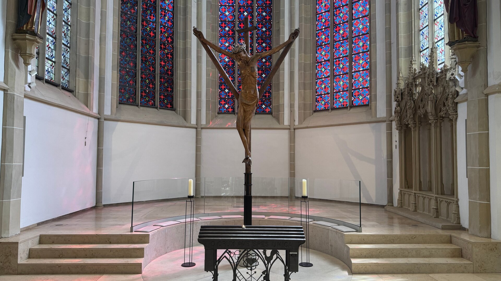 "Katholischer Gottesdienst - Ein Kreuz, das trägt?!": Innenaufnahme: Im Altarraum der Lambertikirche Coesfeld steht das Coesfelder Kreuz vor Buntglasfenstern.