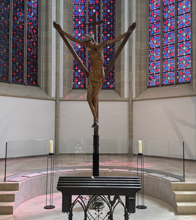 "Katholischer Gottesdienst - Ein Kreuz, das trägt?!": Innenaufnahme: Im Altarraum der Lambertikirche Coesfeld steht das Coesfelder Kreuz vor Buntglasfenstern.
