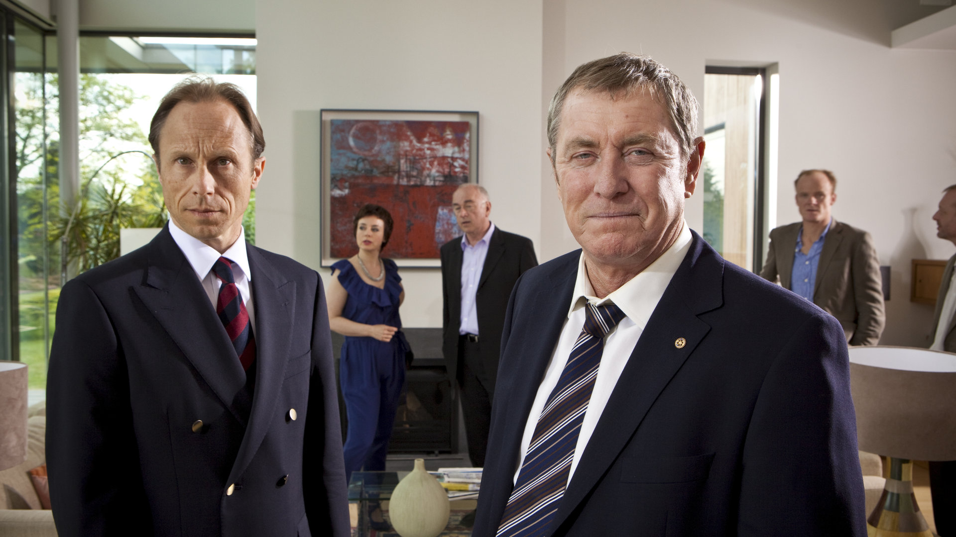 "Inspector Barnaby - Eine Schande für das Dorf": Major David Walsh (David Annen), Liz Gerrard (Amanda Drew), Norman Swanscombe (Peter Egan), DCI Tom Barnaby (John Nettles) und Clifford Bunting (Alistair Petri) stehen alle in einem Wohnzimmer verteilt.