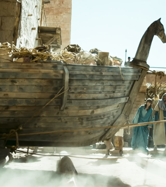 "Die glorreichen 10 - Die legendärsten Schiffe der Geschichte": Die Trojaner ziehen ein mit Schätzen beladenes Schiff durch ihr Stadttor. Den Bug ziert ein hölzerner Pferdekopf.
