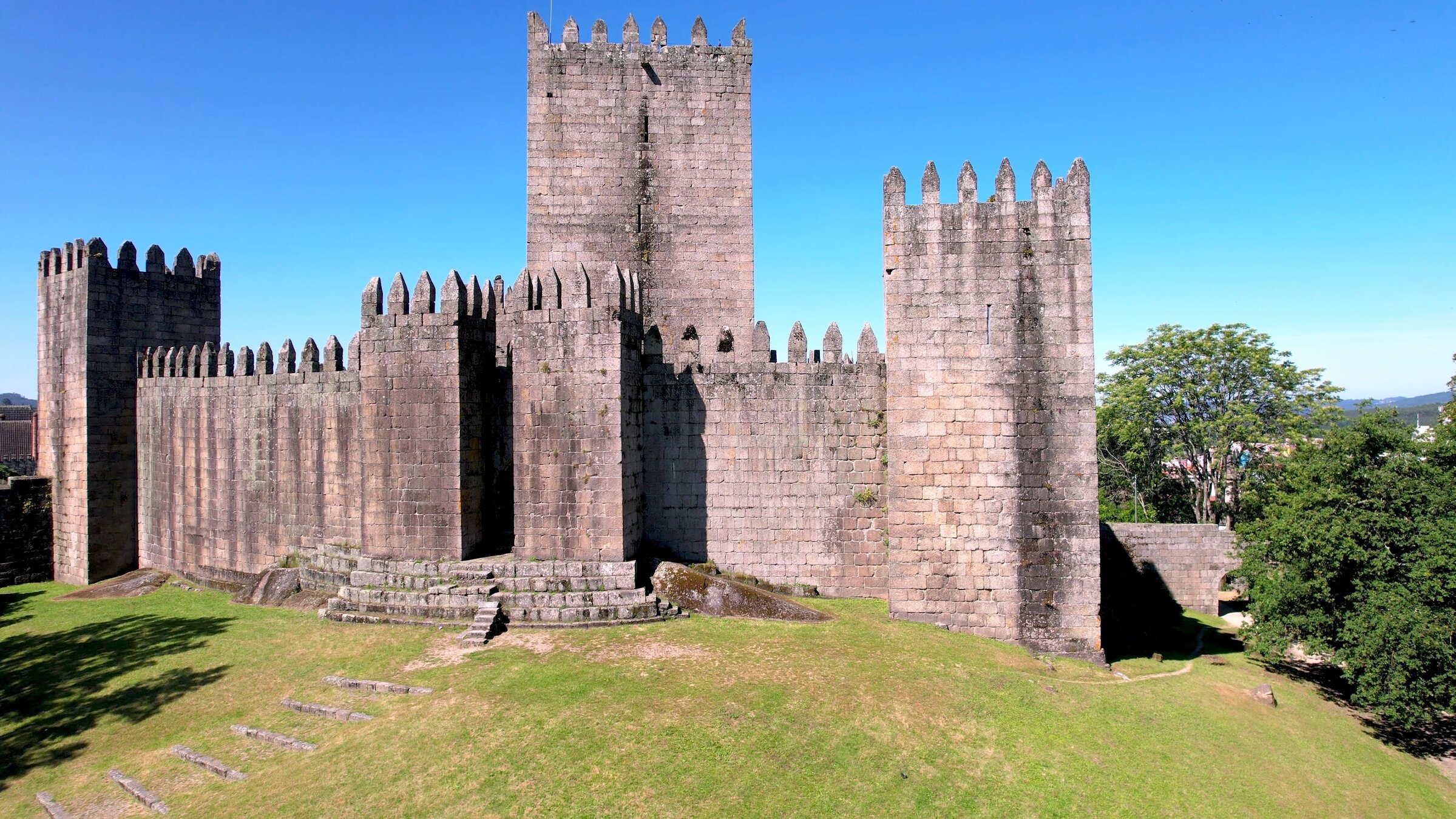 "Im Flug über Portugal": Eine zinnenbewehrte Burg auf grünem Rasen unter blauem Himmel.
