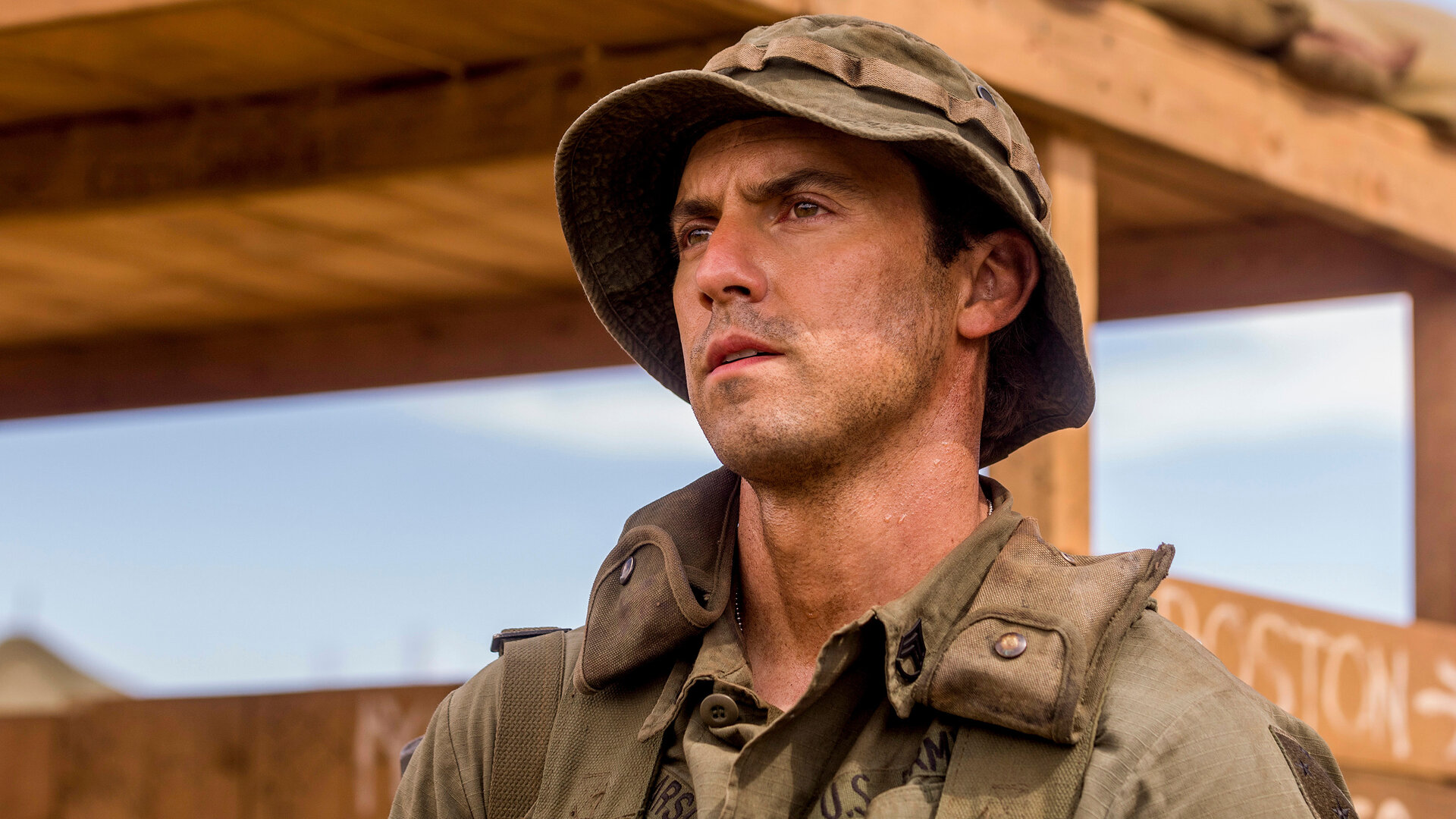 "This Is Us - Sonntagskind": Jack (Milo Ventimiglia) steht auf einem Gelände. Er trägt eine Militäruniform, einen passenden Rucksack über den Schultern sowie einen passenden Hut auf dem Kopf. Sein Gesicht ist leicht mit Staub bedeckt, und er blickt ernst nach vorn.