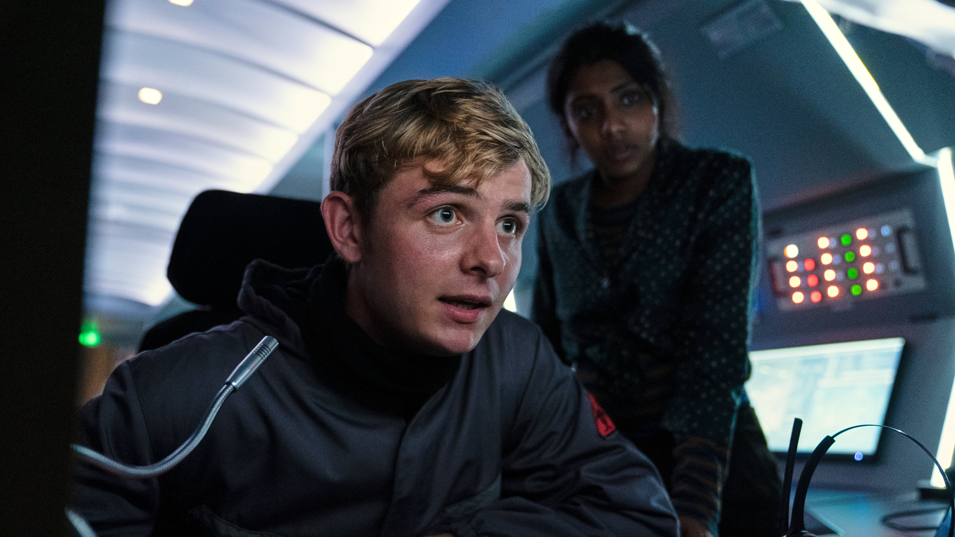 "Alex Rider - Schlag": Alex (Otto Farrant) und Sabina (Charithra Chandran) sitzen angespannt vor einem Kontrollpult.