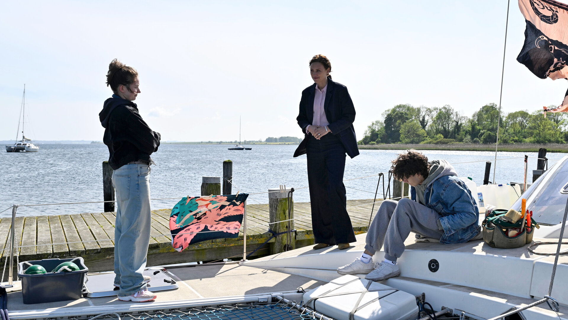 "SOKO Wismar - Verschwunden": Kommissarin Karoline Joost (Nike Fuhrmann) befragt die jungen Straffälligen Vivian (Lorna Zu Solms) und Ilan (Marven Suarez Brinkert) auf dem Katamaran der Bongarts, der zurzeit im Yachthafen liegt.