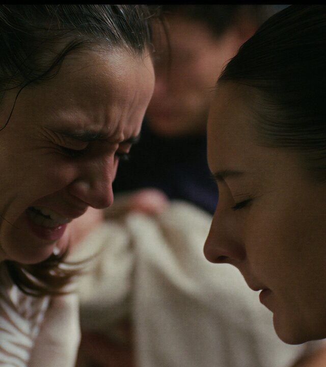 "PUSH - Schicht": Nahaufnahme: Mimi (Laura Balzer) und Elke (Marie Rosa Tietjen) sind fast Kopf an Kopf. Mimi weint und hat ein schmerzverzehrtes Gesicht. Elke strahlt Ruhe aus und blickt nach unten.