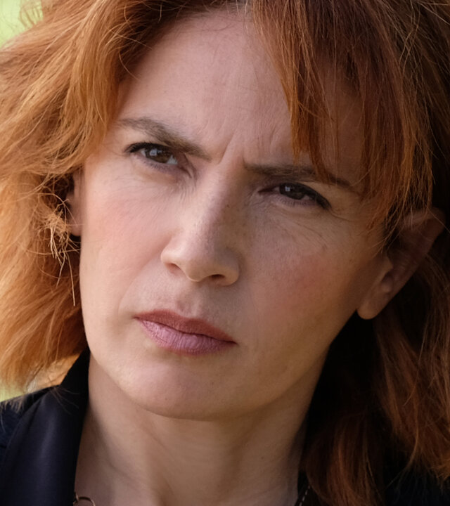 "Standing Tall - Kein Zufall": Nahaufnahme: Sara (Maya Sansa), die Stirn in Falten, blickt mit kritischem Blick Valerio (Alessandro Gassmann) an. Diese ist nur mit einem winzigen Teil des Hinterkopfs im Anschnitt abgebildet. Vor Sara hängt die Gliederkette einer Schaukel.