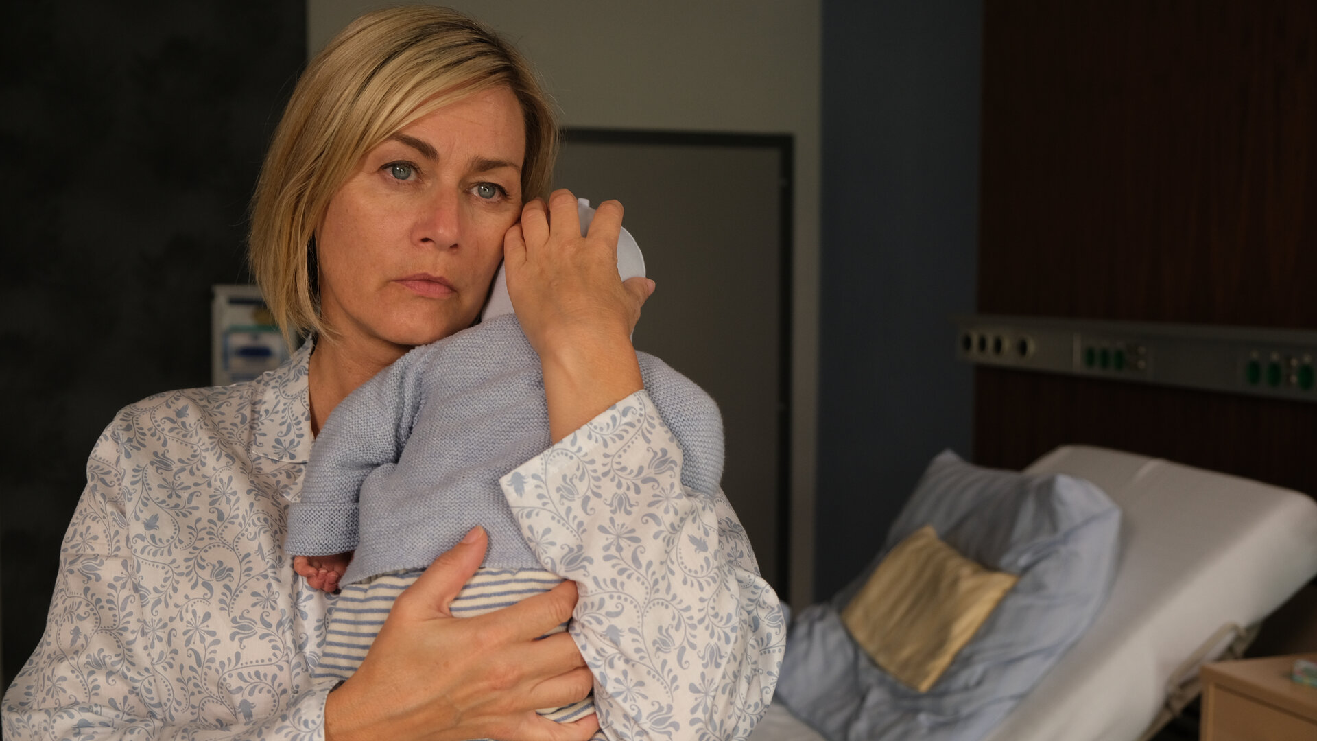"Lena Lorenz - Mutterliebe": In einem Krankenzimmer steht Petra Hoffmann (Gesine Cukrowski) und hält ein Baby auf dem Arm. Sie blickt nachdenklich.