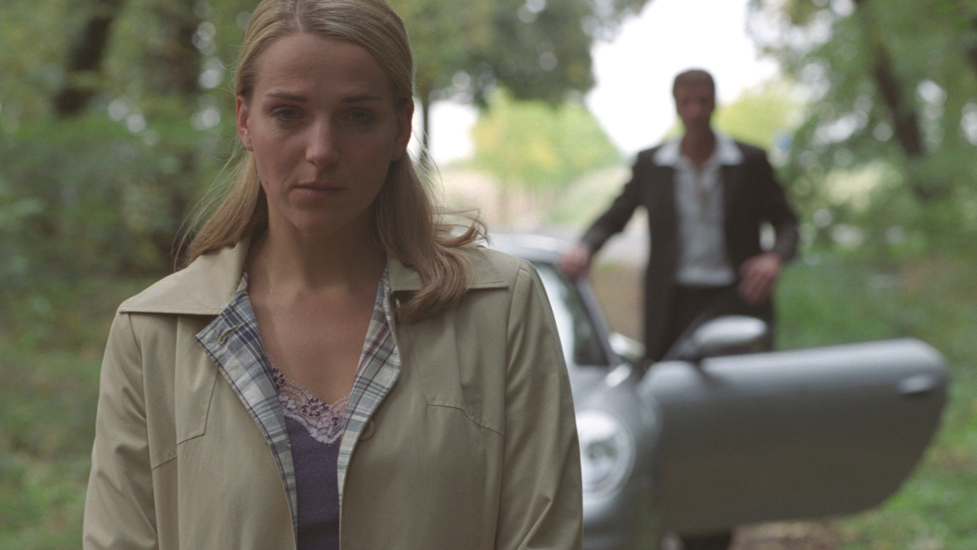 "Bianca - Wege zum Glück: Folge 4": Auf dem Waldweg: Bianca (Tanja Wedhorn) weicht Oliver (Patrick Fichte) aus. Bianca steht vorne im Bild, sie wirkt nachdenklich und traurig. Im Hintergrund verschwommen, steigt Oliver aus einem silbernen Auto.