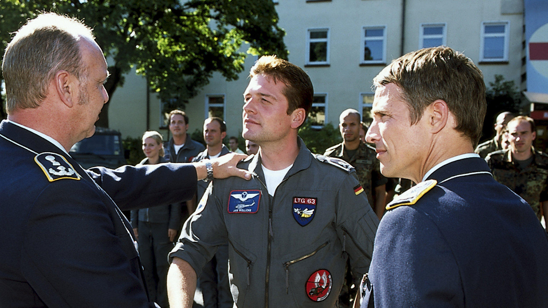 "Die Rettungsflieger - Überraschende Wendung": Dr. Kettwig (Christian Tasche) schüttelt Jan Wollcke (Oliver Hörner) die Hand. Neben ihnen steht Oberst Brandt (Andreas Brucker). Im Hintergrund weitere Soldaten.