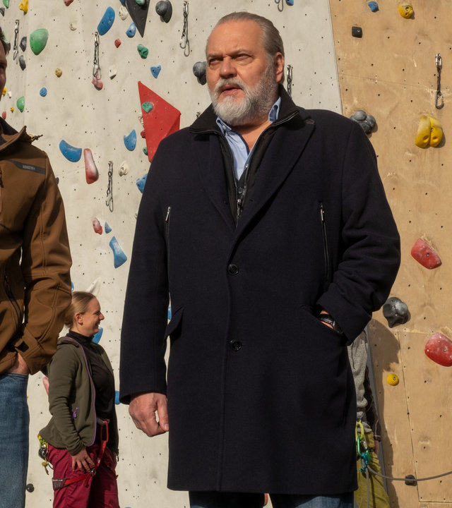 "SOKO Leipzig - Freier Fall": Eric Du Bois (Jonathan Müller) steht mit Hauptkommissar Richard Voss (Jan-Gregor Kremp) im Freien vor einer Kletterwand. Im Hintergrund stehen einige Personen, die sich zum Klettern getroffen haben.